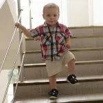 Kind im Alter von 2 bis 3 Jahren läuft selbstbewusst eine Treppe hinunter, zeigt Fortschritte in motorischer Entwicklung wie Rennen, Hüpfen und Treppensteigen.